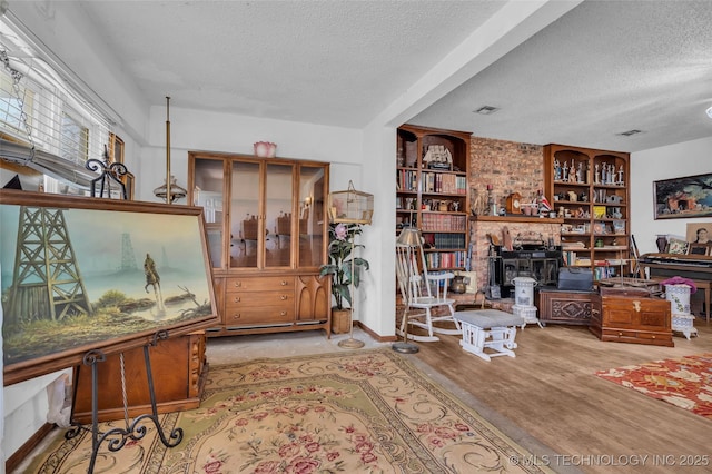 interior space with built in features, a textured ceiling, wood finished floors, and a fireplace