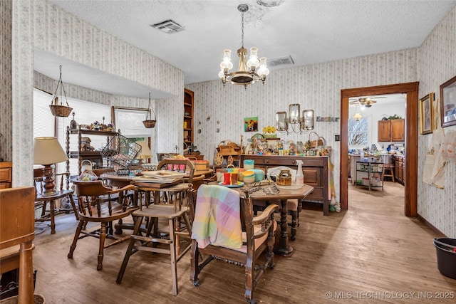 20480 Burneyville, Burneyville, OK 73430 - dining room featuring visible vents, a textured ceiling, wallpapered walls, and wood finished floors
