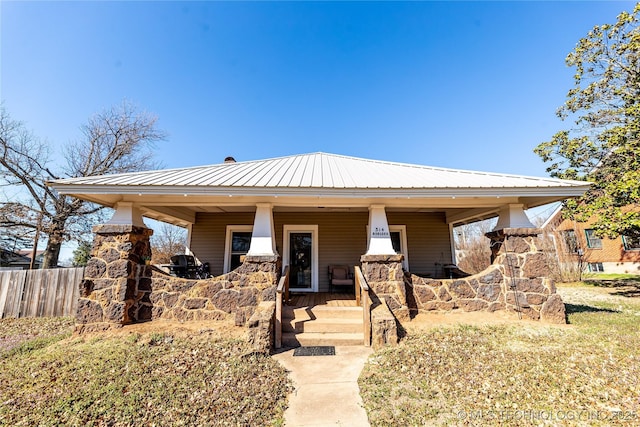 view of front of home with fence, covered porch, and metal roof