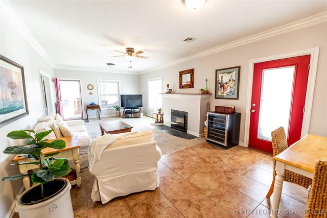 living room featuring visible vents, a fireplace with flush hearth, ornamental molding, a ceiling fan, and wine cooler