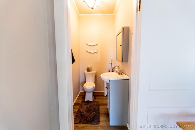 bathroom with vanity, wood finished floors, baseboards, crown molding, and toilet