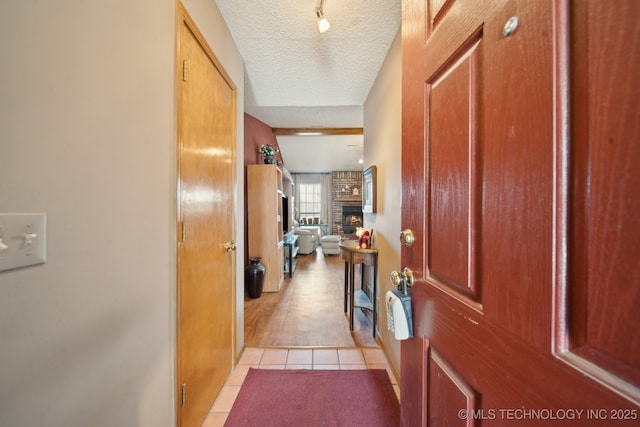 hall featuring light tile patterned floors and a textured ceiling