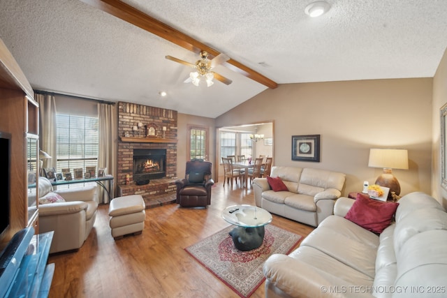 living room with plenty of natural light, a brick fireplace, a ceiling fan, and wood finished floors