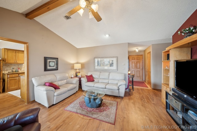 living room with lofted ceiling with beams, a textured ceiling, ceiling fan, and light wood finished floors