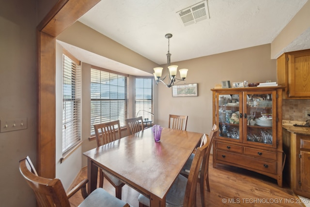 dining room with an inviting chandelier, visible vents, and light wood-type flooring