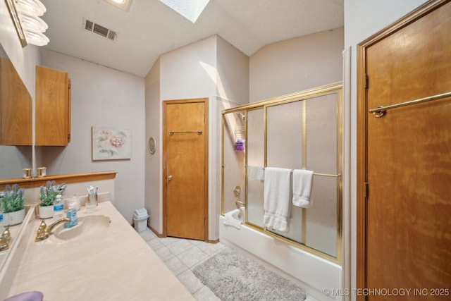 full bath featuring tile patterned flooring, visible vents, a skylight, combined bath / shower with glass door, and vanity