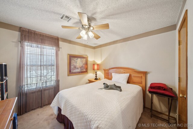 carpeted bedroom with a ceiling fan, visible vents, and a textured ceiling