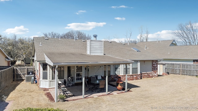 rear view of house with a fenced backyard, central AC, a shingled roof, and a patio area