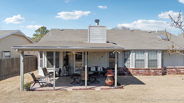 back of property with a patio, a shingled roof, a chimney, and fence