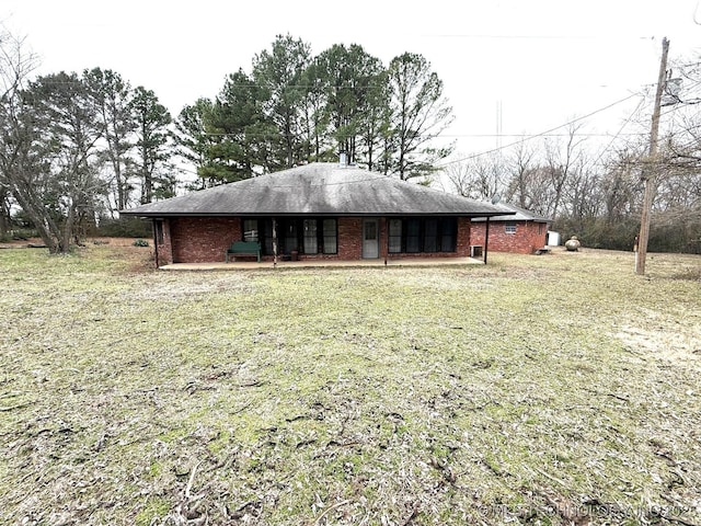 back of house featuring brick siding and a lawn