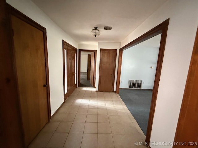 corridor featuring light tile patterned floors, light colored carpet, and visible vents