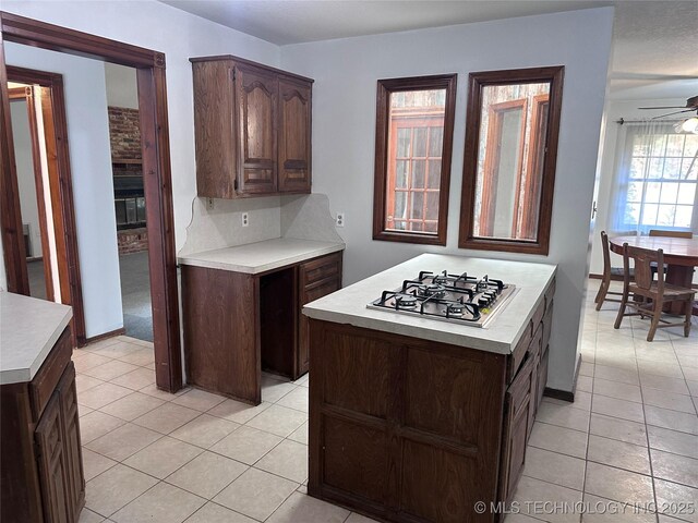 kitchen with decorative backsplash, ceiling fan, light countertops, and stainless steel gas cooktop