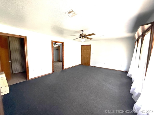 unfurnished bedroom with visible vents, baseboards, dark carpet, a textured ceiling, and a ceiling fan