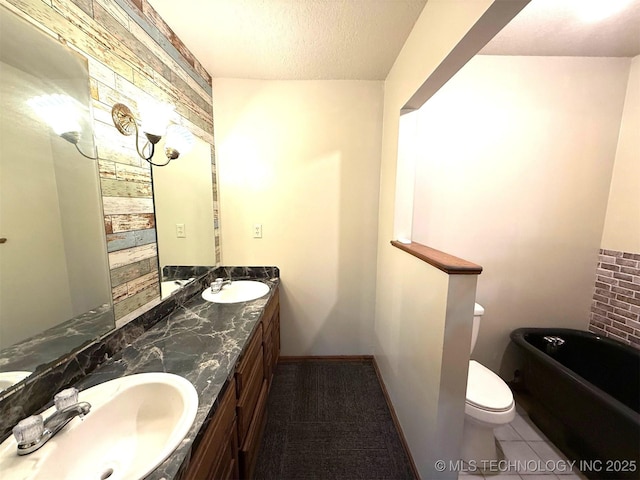 bathroom with a textured ceiling, double vanity, toilet, and a sink