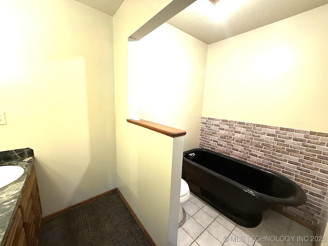 bathroom with tile patterned flooring, a tub, baseboards, toilet, and vanity