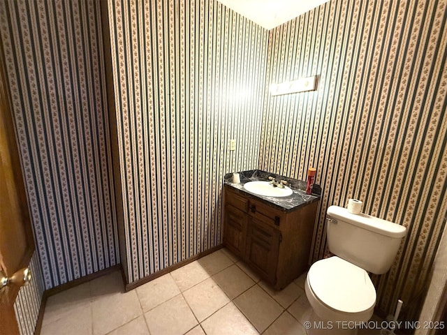 half bathroom featuring tile patterned flooring, wallpapered walls, baseboards, toilet, and vanity