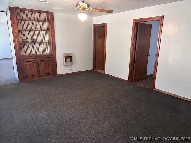 empty room featuring a ceiling fan, heating unit, a textured ceiling, carpet, and baseboards