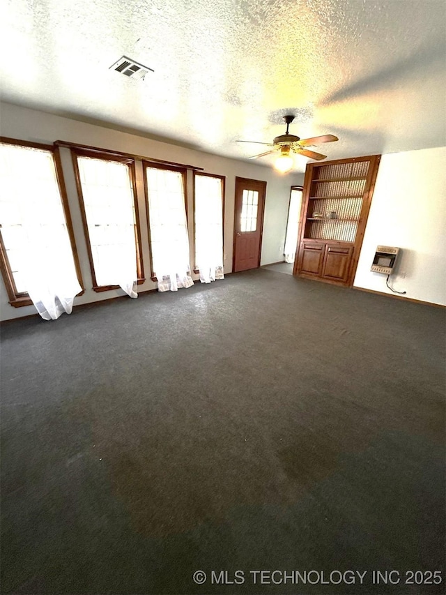 unfurnished living room with ceiling fan, visible vents, dark colored carpet, and a textured ceiling