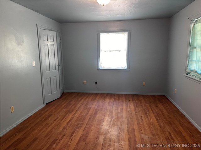 spare room with a wealth of natural light, baseboards, and wood finished floors