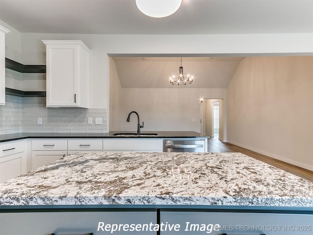 kitchen featuring a sink, decorative backsplash, stainless steel dishwasher, and white cabinetry