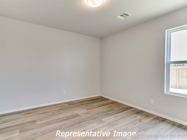 empty room featuring visible vents, baseboards, and light wood-style floors