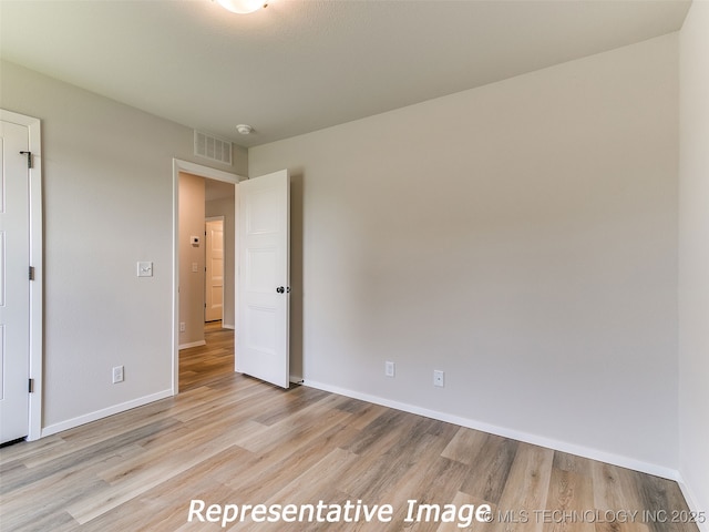 unfurnished bedroom featuring baseboards, visible vents, and light wood finished floors