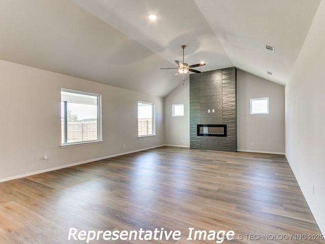 unfurnished living room featuring visible vents, wood finished floors, a large fireplace, ceiling fan, and vaulted ceiling