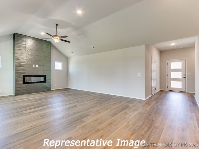 unfurnished living room with a wealth of natural light, light wood-type flooring, a large fireplace, and baseboards