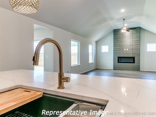 interior space with light stone counters, a healthy amount of sunlight, open floor plan, and a large fireplace