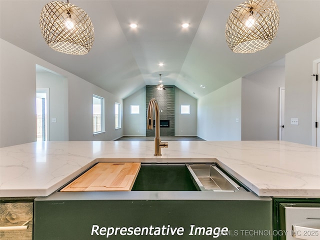 kitchen featuring green cabinets, open floor plan, lofted ceiling, light stone counters, and a ceiling fan