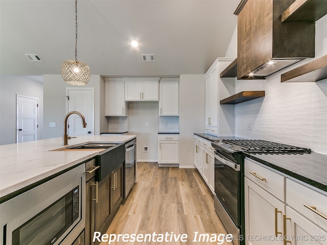 kitchen with visible vents, open shelves, dark stone counters, stainless steel appliances, and wall chimney exhaust hood