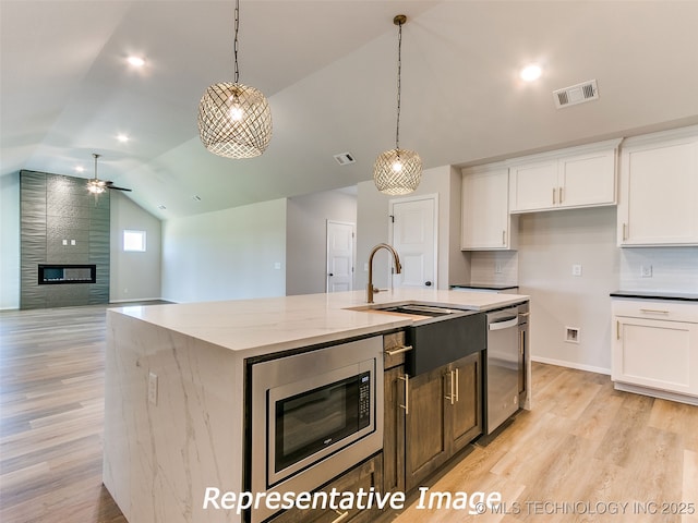 kitchen featuring visible vents, white cabinets, appliances with stainless steel finishes, and vaulted ceiling