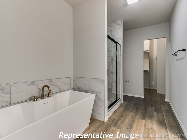 bathroom with a freestanding tub, a walk in closet, wood finished floors, and a shower stall