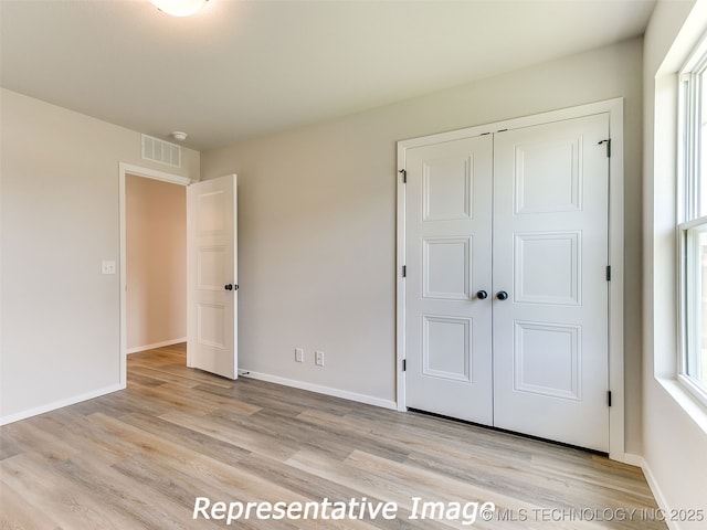 unfurnished bedroom featuring baseboards, visible vents, and light wood-type flooring