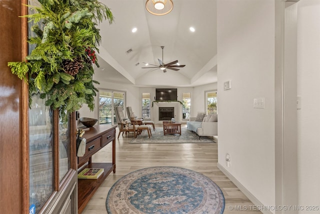 living area with a ceiling fan, high vaulted ceiling, recessed lighting, a fireplace, and light wood-type flooring