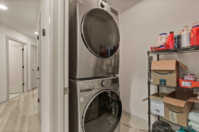 washroom with laundry area, stacked washer / dryer, and wood finished floors