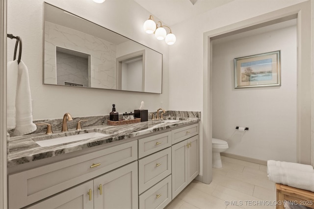 bathroom with double vanity, toilet, baseboards, and a sink