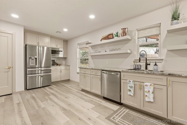 kitchen featuring plenty of natural light, appliances with stainless steel finishes, open shelves, and a sink