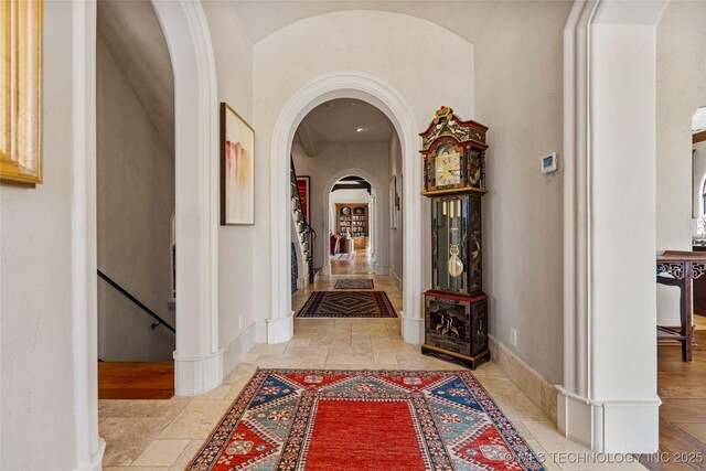 3217 E 61st Pl, Tulsa, OK 74136 - hall featuring arched walkways, stone tile flooring, and baseboards