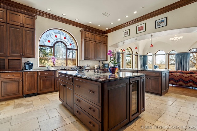 3217 E 61st Pl, Tulsa, OK 74136 - kitchen featuring stone tile floors, ornamental molding, and an island with sink
