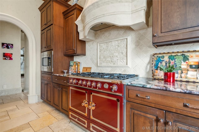 3217 E 61st Pl, Tulsa, OK 74136 - kitchen with stainless steel microwave, decorative backsplash, range with two ovens, custom exhaust hood, and arched walkways