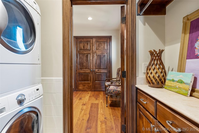 3217 E 61st Pl, Tulsa, OK 74136 - washroom featuring recessed lighting, cabinet space, stacked washer / drying machine, and light wood-style flooring