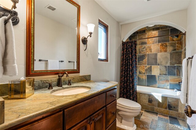 3217 E 61st Pl, Tulsa, OK 74136 - full bath featuring stone finish floor, visible vents, tiled shower / bath, toilet, and vanity