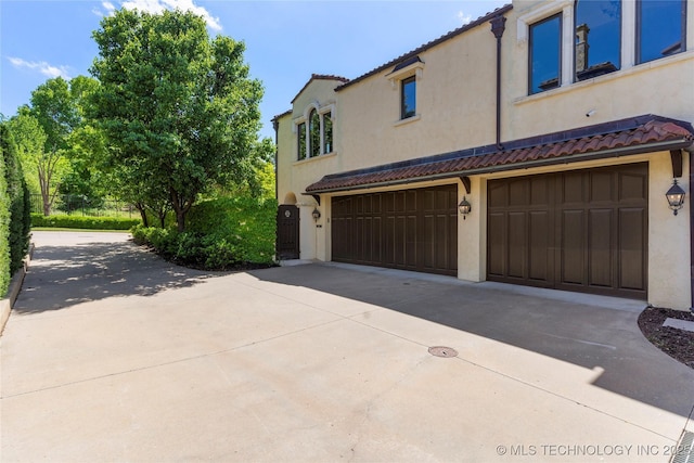 3217 E 61st Pl, Tulsa, OK 74136 - view of side of property featuring driveway, a tile roof, stucco siding, and a garage