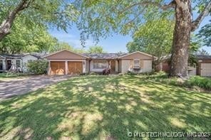 ranch-style house featuring a front lawn, a garage, and driveway