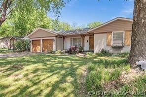 view of front facade featuring driveway, an attached garage, and a front lawn