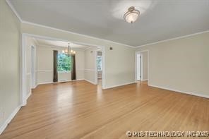 unfurnished room featuring an inviting chandelier, wood finished floors, and crown molding