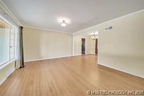 spare room with visible vents, baseboards, wood finished floors, and crown molding