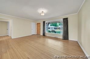 spare room with wood finished floors, baseboards, and ornamental molding