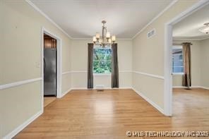 unfurnished dining area featuring a chandelier, crown molding, and wood finished floors